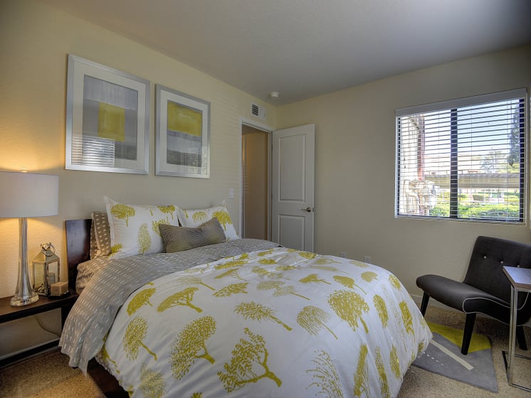 Master Bedroom with White Comforter with Golden Tree Design Pattern, Carpet, Gray Chair and Window